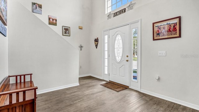 foyer entrance featuring dark wood-type flooring and a towering ceiling