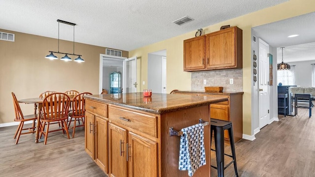 kitchen with hardwood / wood-style flooring, a textured ceiling, a center island, and hanging light fixtures