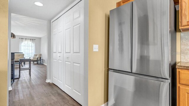 kitchen featuring tasteful backsplash, light wood-type flooring, and stainless steel fridge