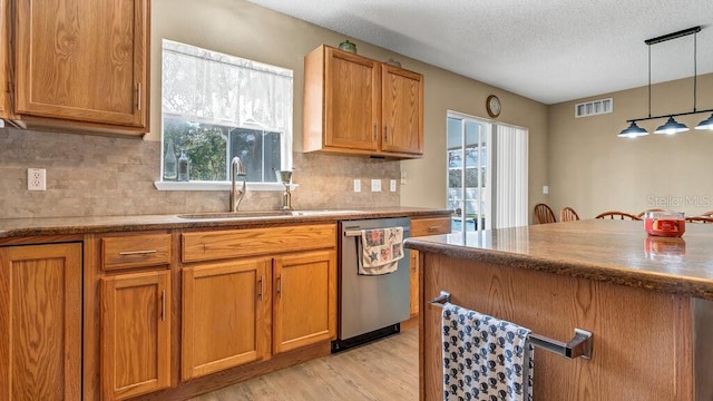 kitchen with a textured ceiling, dishwasher, a wealth of natural light, and decorative light fixtures