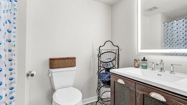 bathroom with vanity, toilet, and a textured ceiling