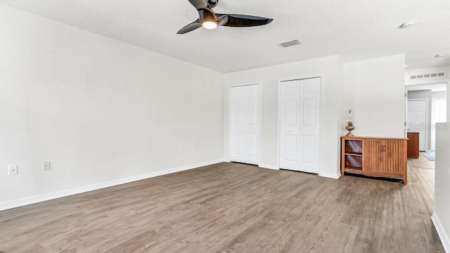 unfurnished bedroom with a textured ceiling, dark hardwood / wood-style floors, and ceiling fan