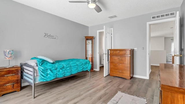 bedroom with a textured ceiling, wood-type flooring, and ceiling fan