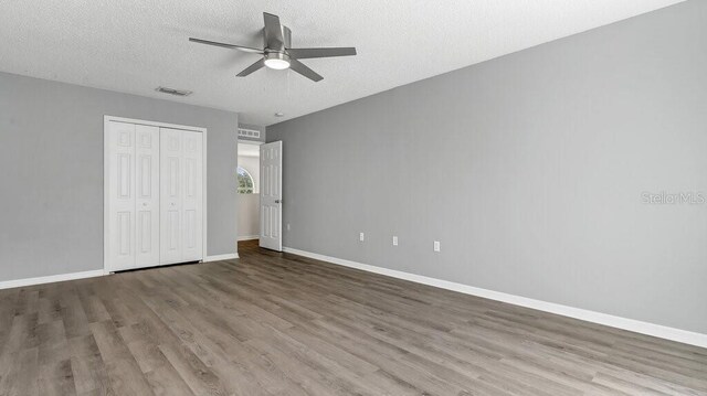 unfurnished bedroom featuring a closet, hardwood / wood-style floors, a textured ceiling, and ceiling fan