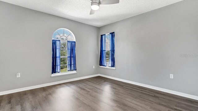 unfurnished room with a textured ceiling, ceiling fan, and dark hardwood / wood-style flooring