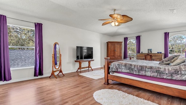 bedroom featuring ceiling fan, hardwood / wood-style flooring, and a textured ceiling