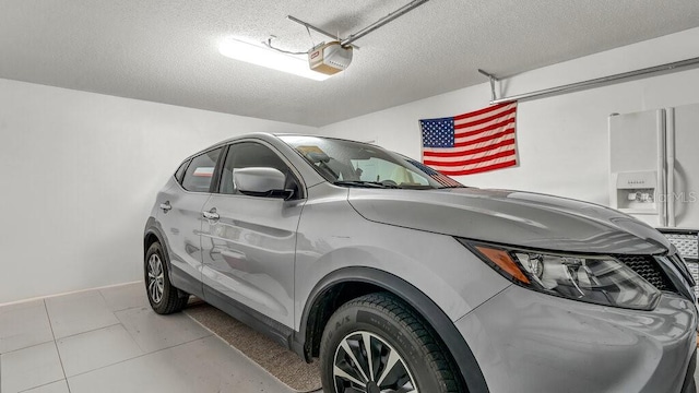 garage featuring a garage door opener and white refrigerator with ice dispenser