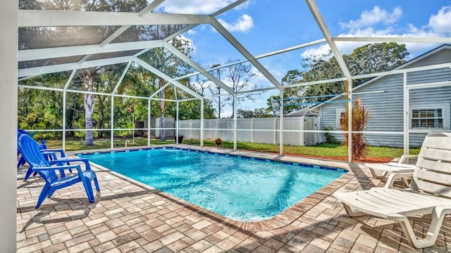 view of pool featuring a patio area, a storage unit, and glass enclosure