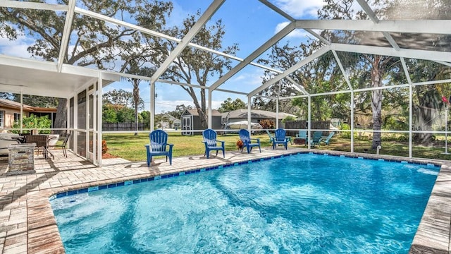 view of pool with a yard, a shed, a patio, and a lanai