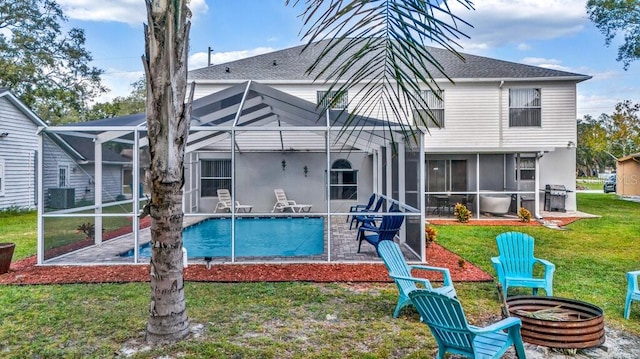 back of property with central air condition unit, an outdoor fire pit, a lawn, a patio, and glass enclosure