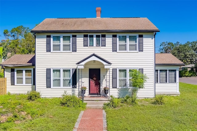 colonial-style house featuring a front lawn