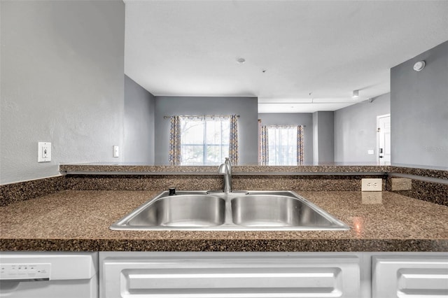 kitchen with dishwashing machine, sink, and white cabinets