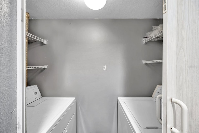 laundry area featuring a textured ceiling and washing machine and clothes dryer