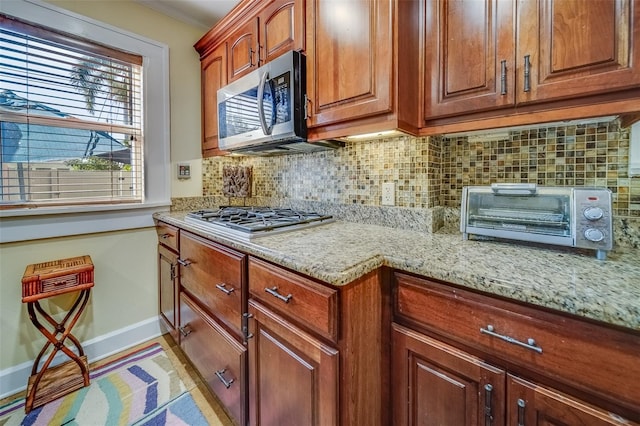 kitchen with appliances with stainless steel finishes, light stone counters, and backsplash