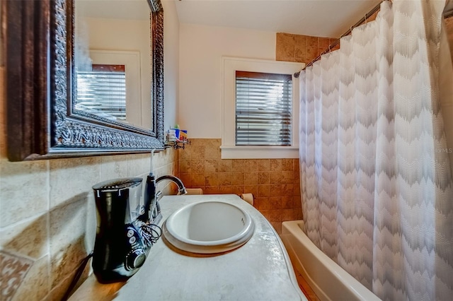 bathroom with sink, shower / bath combo with shower curtain, a wealth of natural light, and tile walls