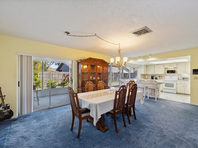 dining room featuring carpet floors, a chandelier, and a textured ceiling