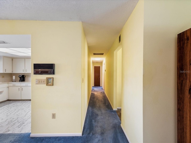 hallway featuring a textured ceiling and carpet floors