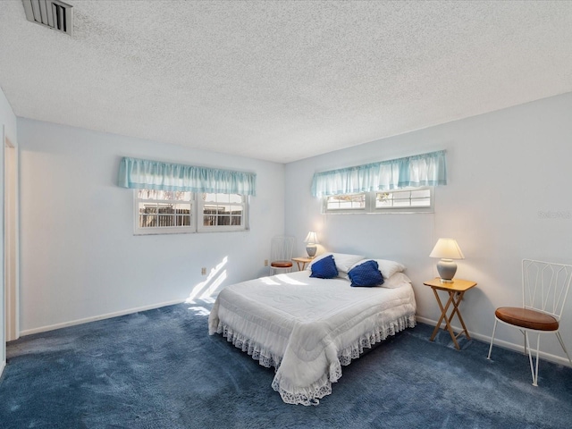 bedroom featuring a textured ceiling and dark carpet