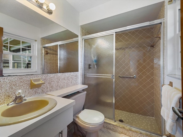 bathroom with toilet, a textured ceiling, vanity, and a shower with door