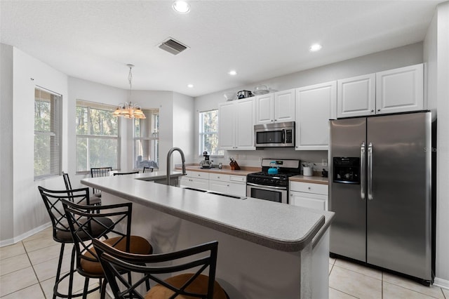 kitchen featuring a wealth of natural light, white cabinetry, a kitchen island with sink, and appliances with stainless steel finishes