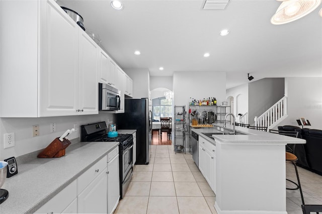 kitchen featuring white cabinetry, sink, a kitchen bar, light tile patterned floors, and appliances with stainless steel finishes