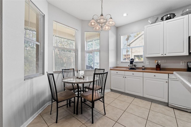 kitchen with white cabinetry, light tile patterned floors, hanging light fixtures, and white dishwasher