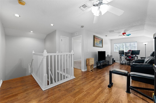 living room with lofted ceiling, ceiling fan, wood-type flooring, and a textured ceiling