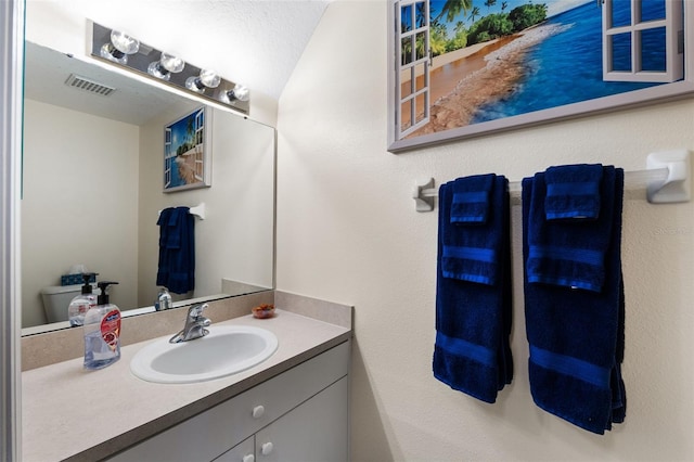 bathroom featuring vanity, a textured ceiling, and toilet