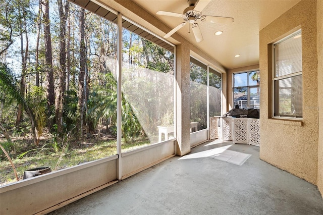 unfurnished sunroom featuring ceiling fan and a healthy amount of sunlight