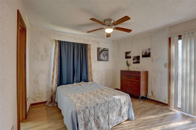 bedroom featuring a textured ceiling, wood finished floors, a ceiling fan, and baseboards