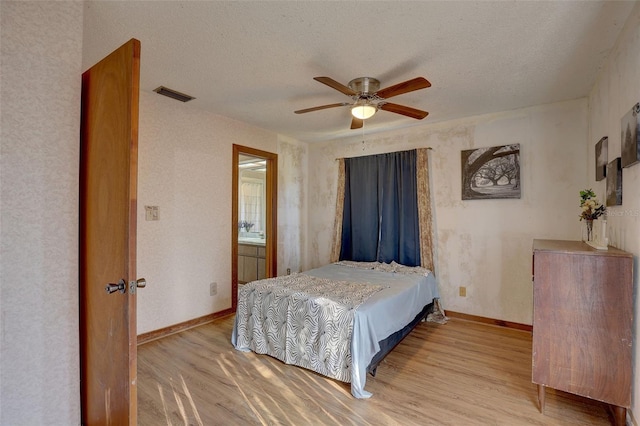 bedroom featuring light wood finished floors, baseboards, visible vents, and a textured ceiling