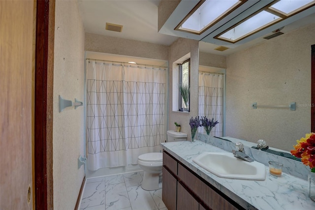 bathroom with a skylight, visible vents, toilet, marble finish floor, and vanity