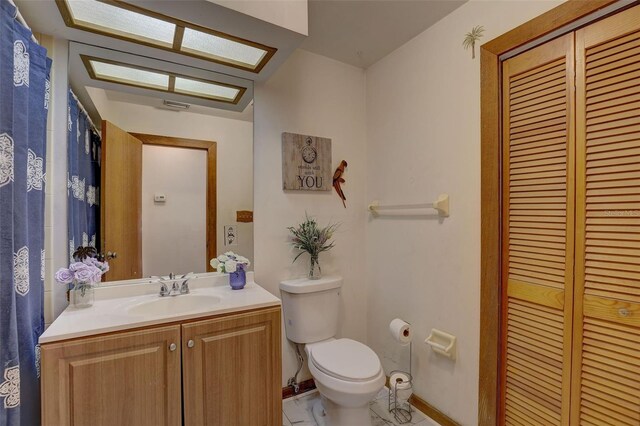 bathroom featuring toilet, visible vents, vanity, baseboards, and a closet