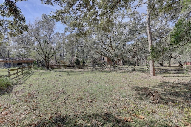 view of yard with fence and a rural view