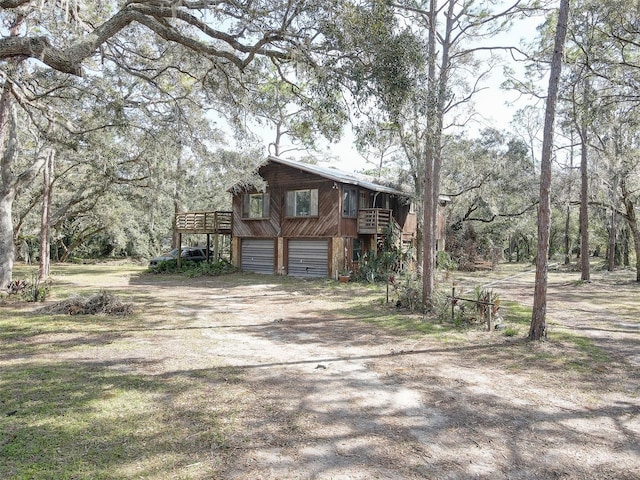 view of front of house with a garage, driveway, a deck, and stairs