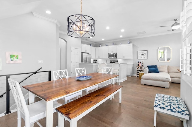 dining space featuring ornamental molding, light hardwood / wood-style flooring, and ceiling fan with notable chandelier