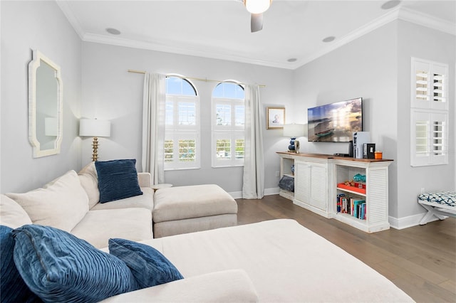 living room with ornamental molding, dark wood-type flooring, and ceiling fan