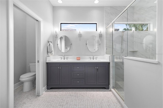 bathroom featuring vanity, toilet, a shower with shower door, and a wealth of natural light