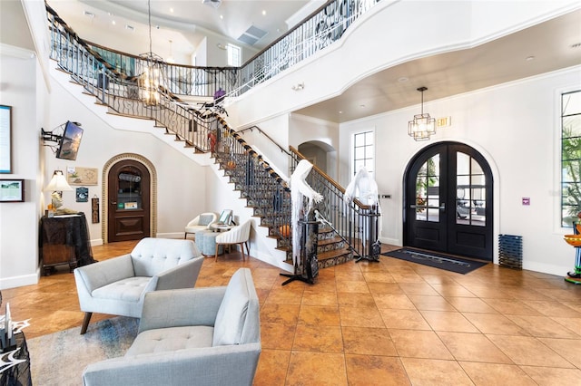 foyer with french doors, crown molding, tile patterned floors, and a towering ceiling