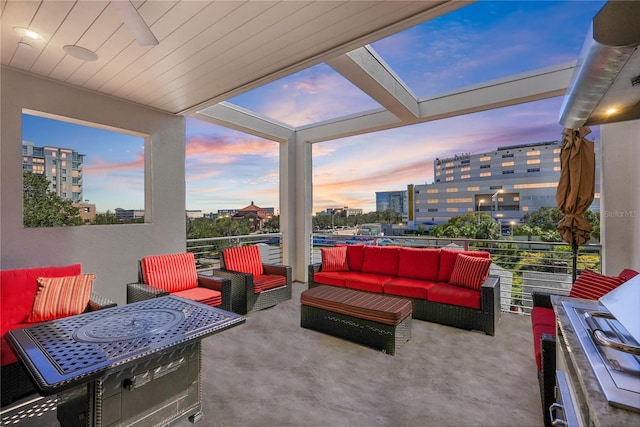 patio terrace at dusk featuring a balcony and an outdoor hangout area