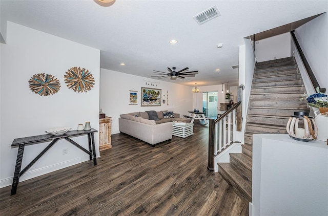 living room with ceiling fan with notable chandelier and dark hardwood / wood-style floors