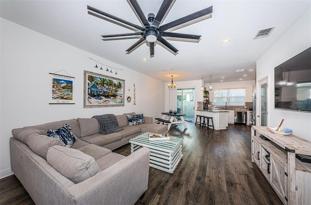 living room with dark wood-type flooring, sink, and ceiling fan with notable chandelier