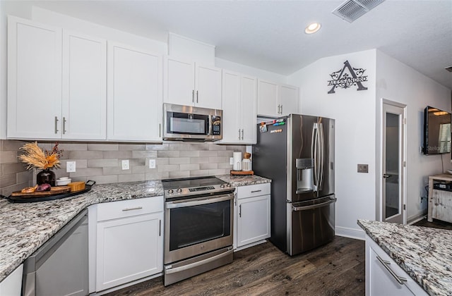 kitchen with appliances with stainless steel finishes, white cabinetry, light stone counters, and dark wood-type flooring