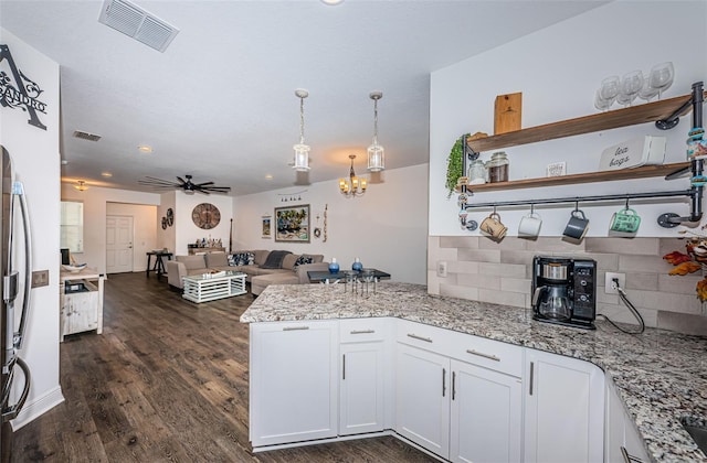 kitchen with dark hardwood / wood-style flooring, white cabinetry, ceiling fan with notable chandelier, pendant lighting, and light stone counters