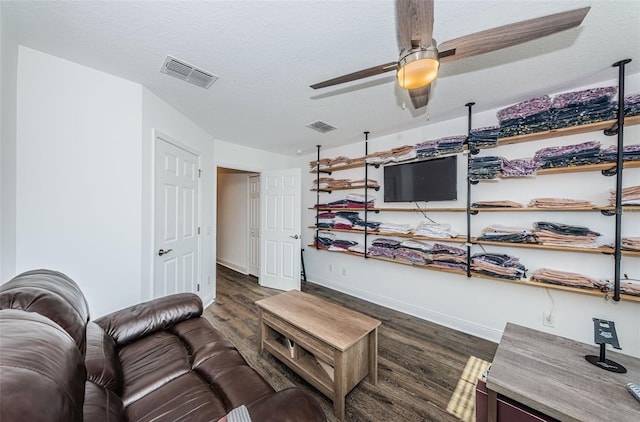 living room with dark wood-type flooring, a textured ceiling, and ceiling fan