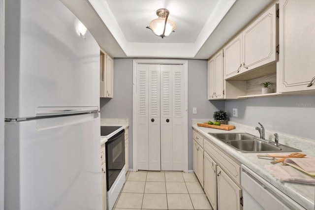 kitchen with white appliances, light tile patterned floors, a tray ceiling, and sink