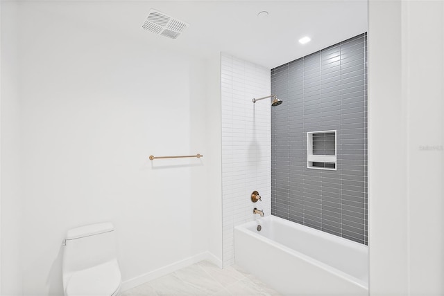 bathroom with toilet and tiled shower / bath combo