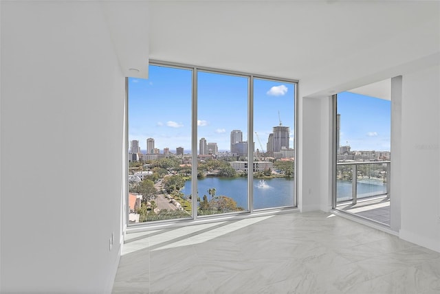 spare room featuring a water view, a healthy amount of sunlight, and expansive windows