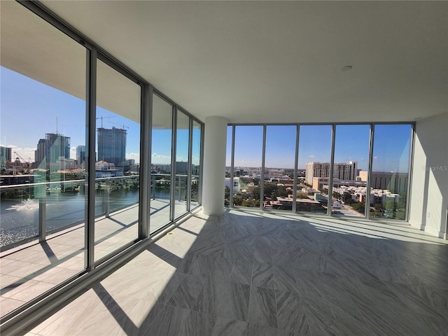 unfurnished bedroom featuring a water view and floor to ceiling windows