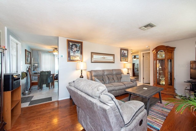 living room featuring ceiling fan and dark hardwood / wood-style floors